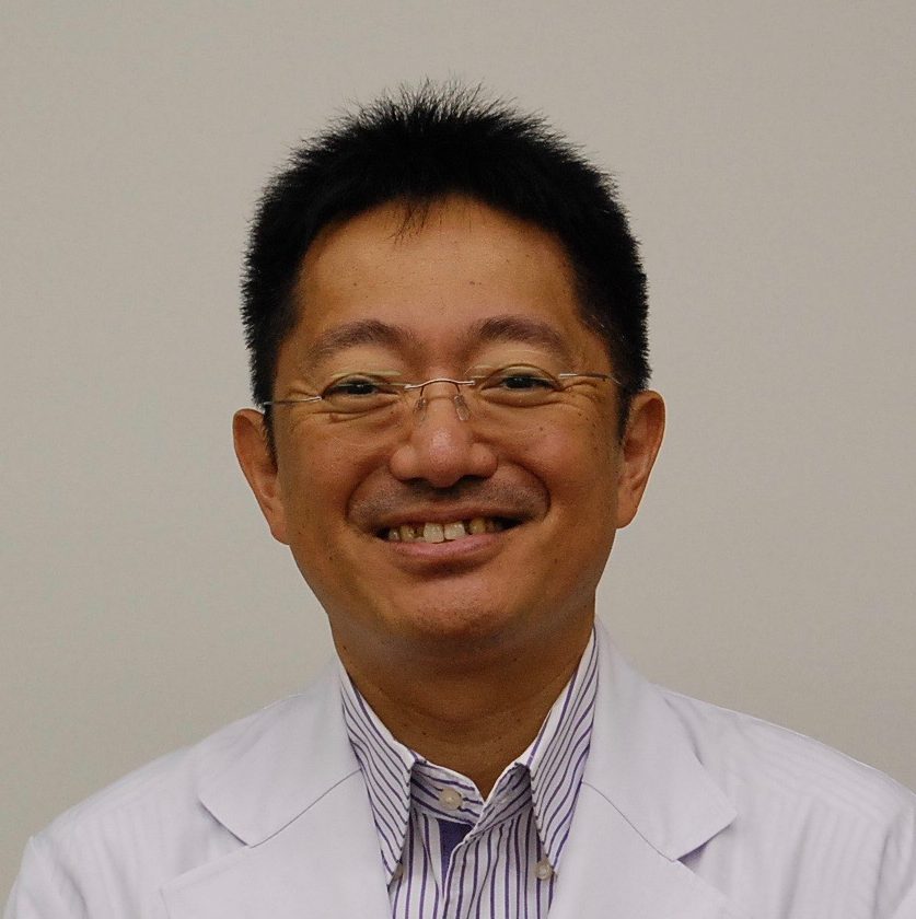 福島県立医科大学の准教授、藤井正純氏の笑顔のポートレート。白衣を着用し、医療に従事する姿勢が伺える。