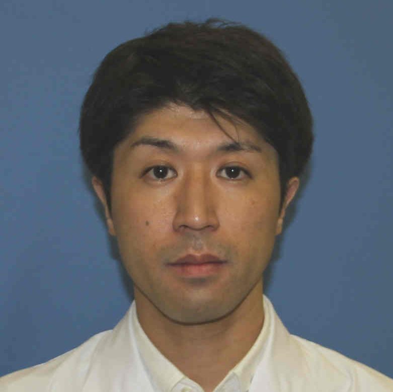 医療従事者の男性が白衣を着ているポートレート写真。背景は青色。