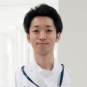 医療現場で微笑む男性医師のポートレート。白衣を着用し、背景は明るい病院内。