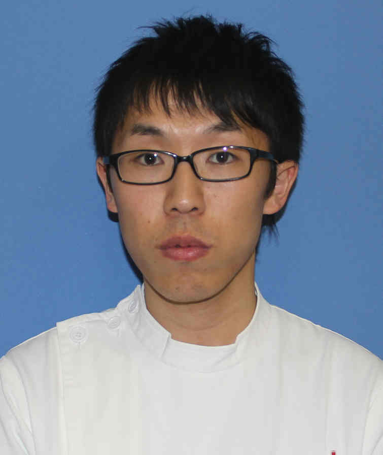 医療従事者の男性が白衣を着て、青い背景の前で真剣な表情をしている写真。