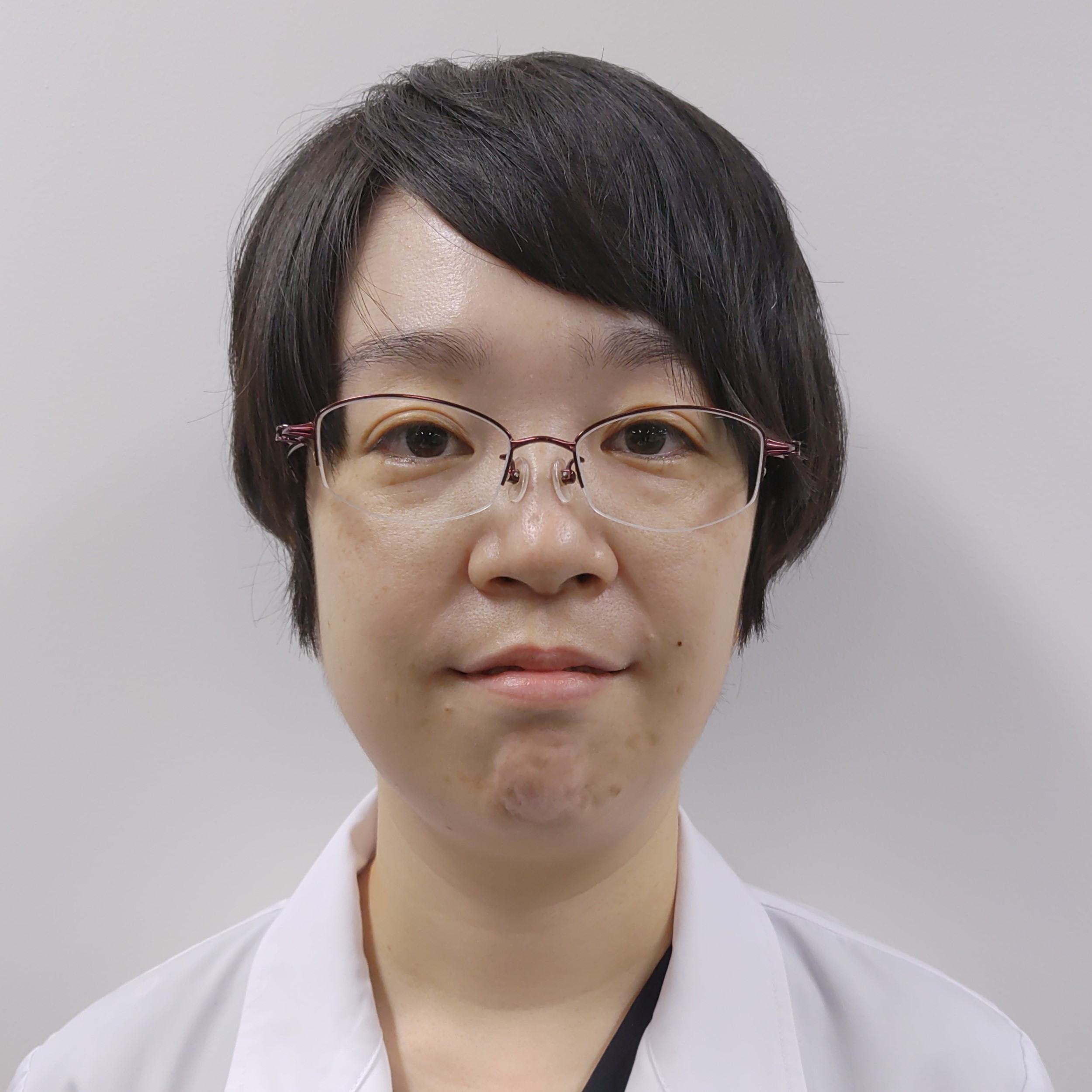 医療白衣を着た女性がカメラに向かって微笑んでいるポートレート。