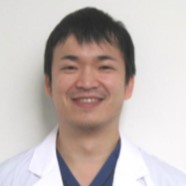 医療用白衣を着た男性が微笑んでいるポートレート。福島県立医科大学の助手として活動している。