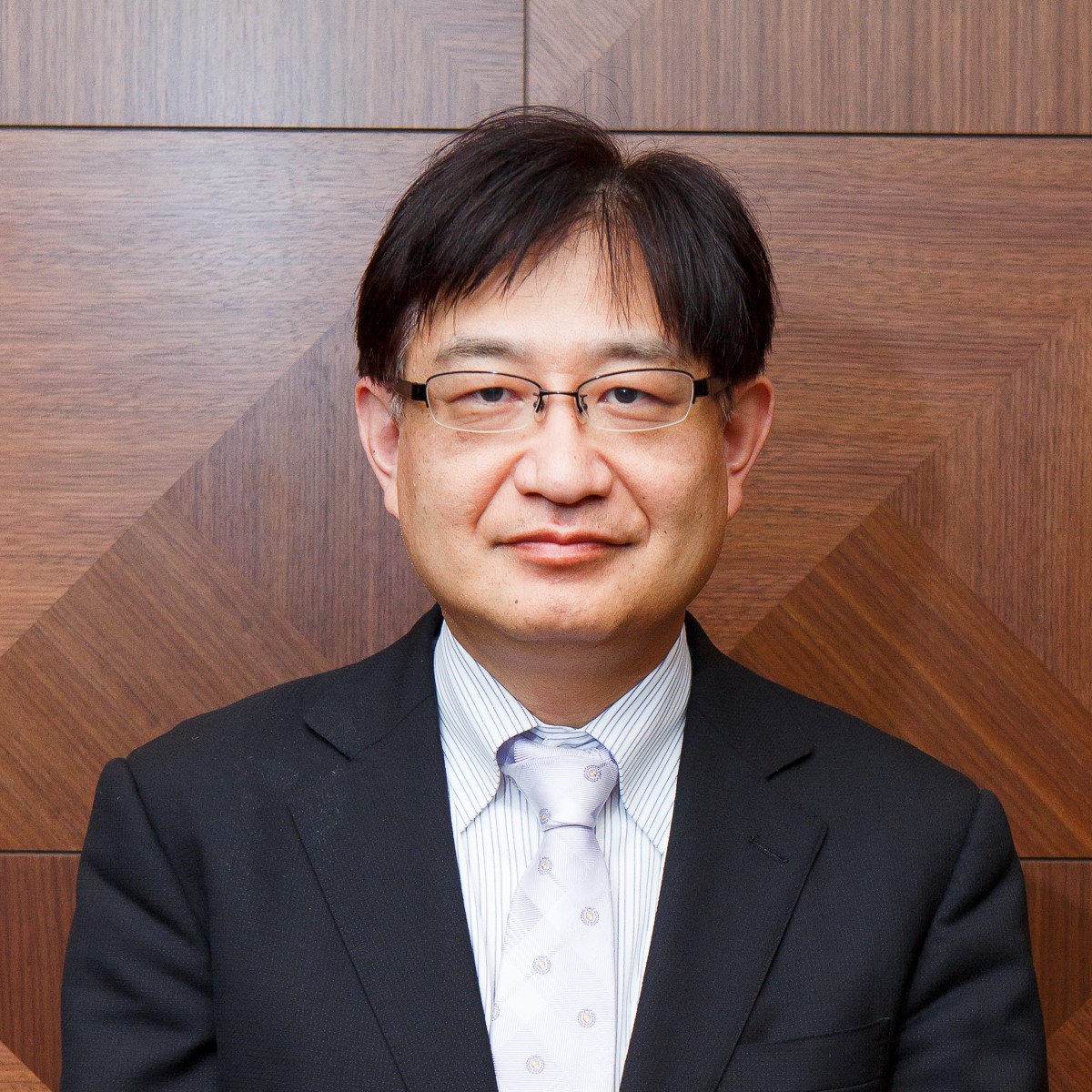 福島県立医科大学の池田和彦教授がスーツを着て微笑んでいるポートレート。背景は木目調の壁。