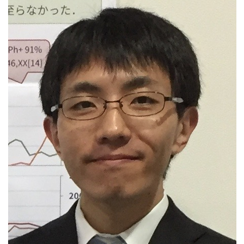 深津真彦氏が研究発表を行っている様子。背景にはグラフやデータが表示されたポスターが見える。