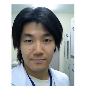 医療現場での研究者のポートレート、白衣を着た男性がカメラを見つめている。