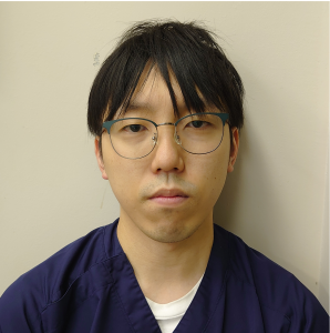 医療技師の男性が青い医療用の服を着て、真剣な表情でカメラを見つめているポートレート。
