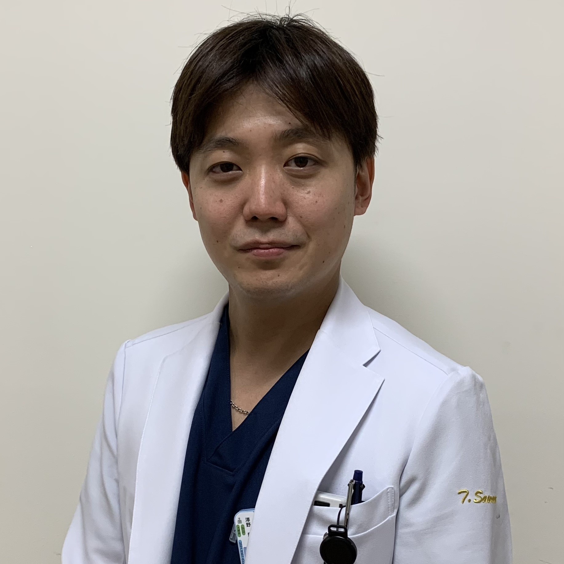 医療用白衣を着た男性がカメラに向かって微笑んでいるポートレート。