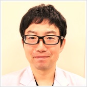 名取穣助教のポートレート。白衣を着て、眼鏡をかけた医師の写真。