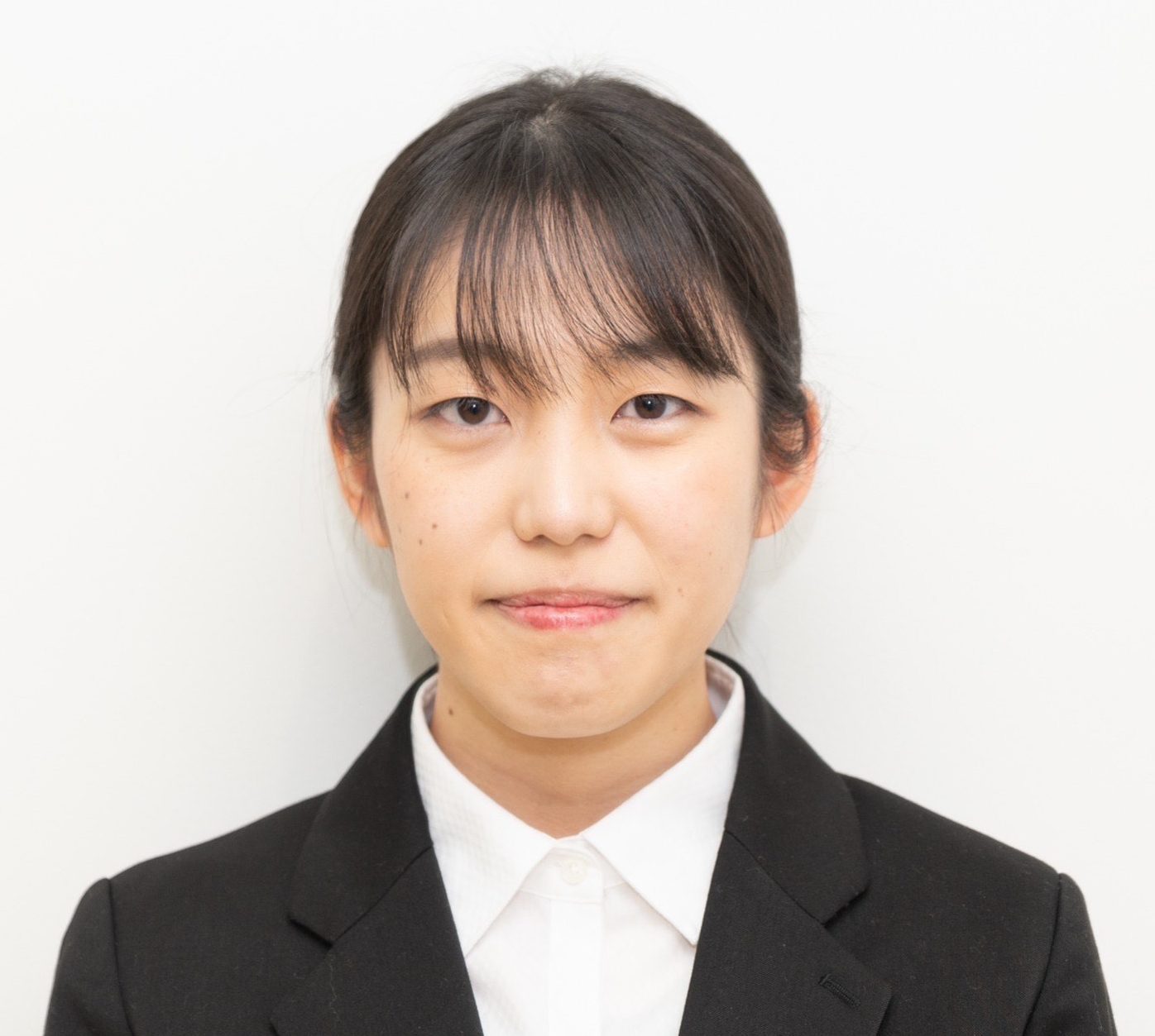 医療関係の服装をした女性が、白い背景の前で微笑んでいるポートレート。