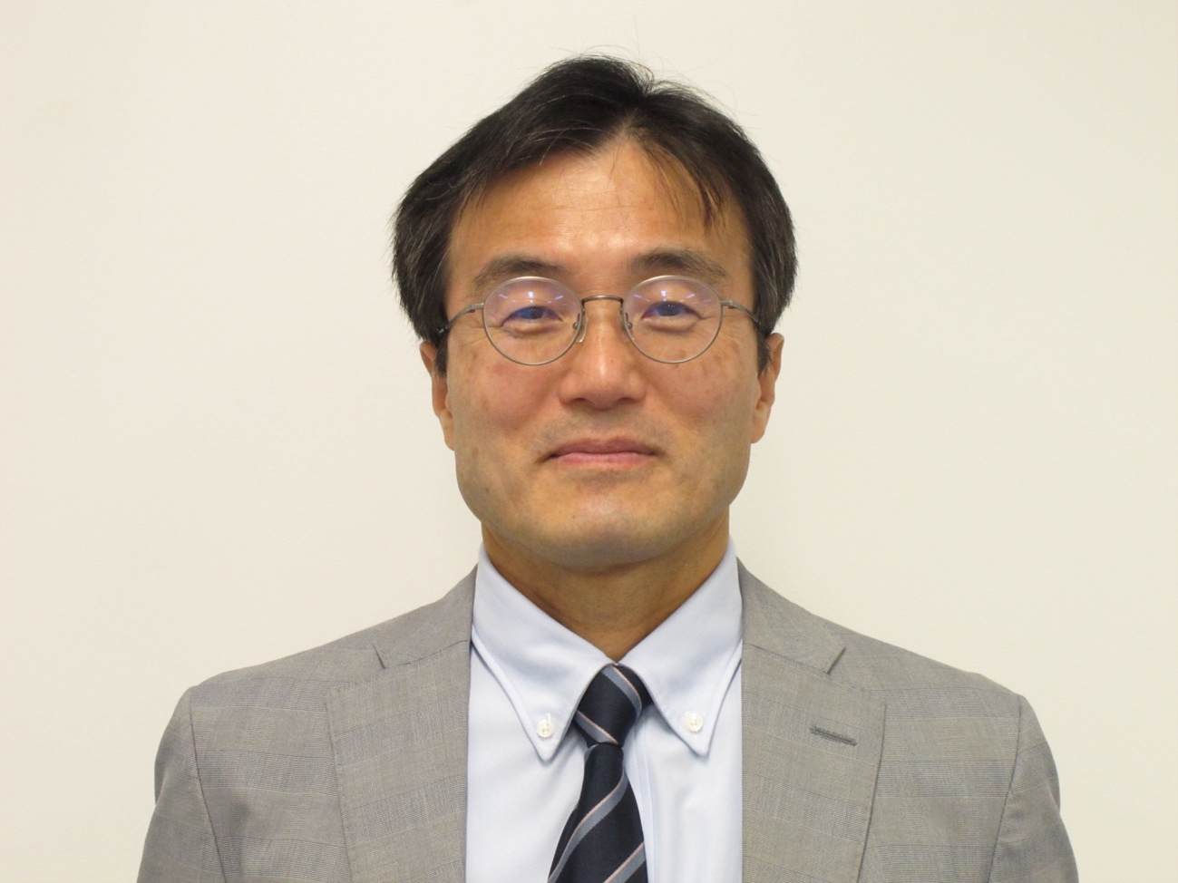 福島県立医科大学の坂井晃教授がスーツ姿で微笑んでいるポートレート。