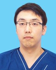 齋藤宏章博士が青い背景の前で医療用の服を着ているポートレート。