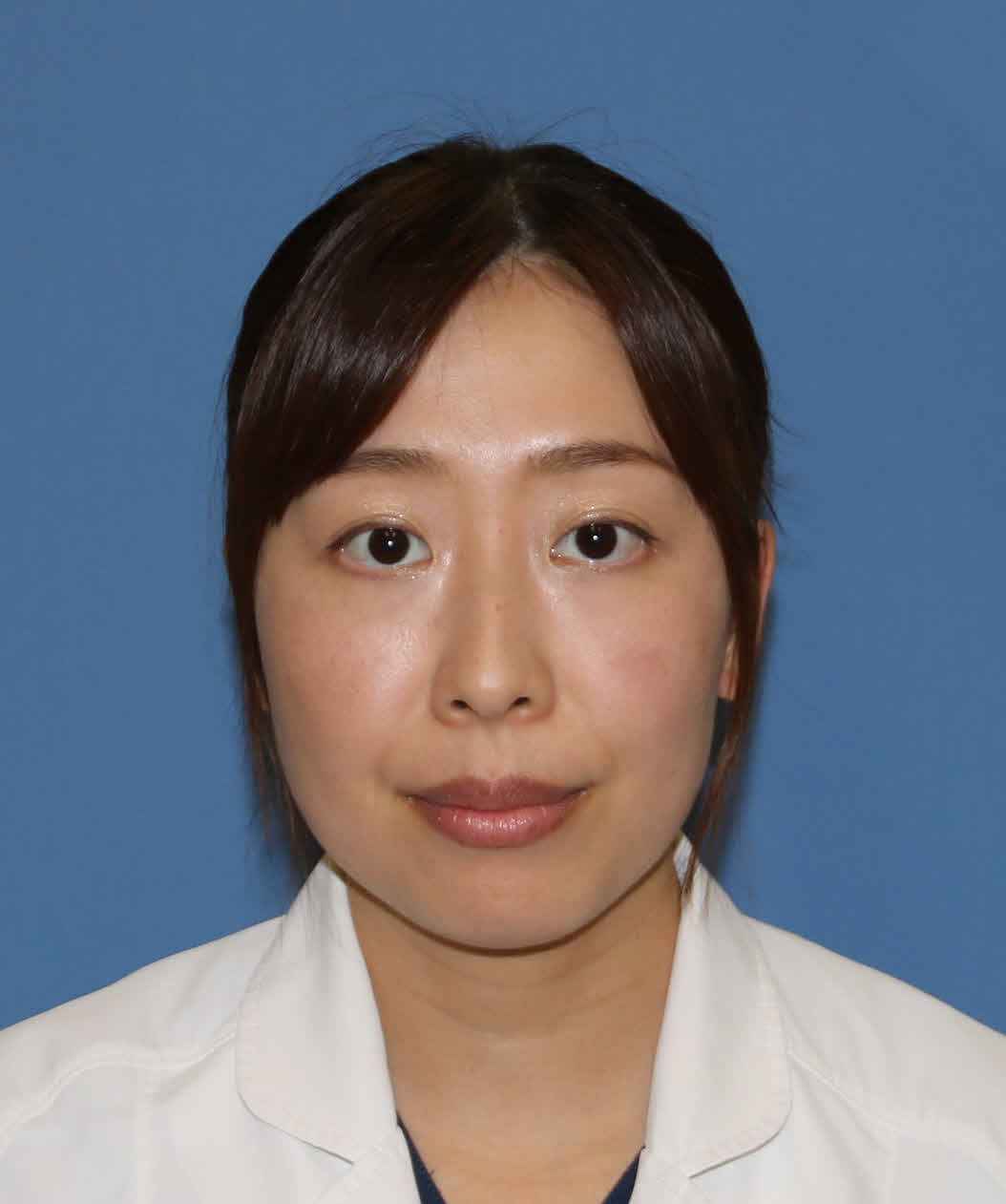 医療白衣を着た女性のポートレート。背景は青色で、真剣な表情を浮かべている。