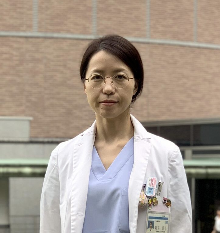 医療用白衣を着た女性が、福島県立医科大学の前で立っている姿。