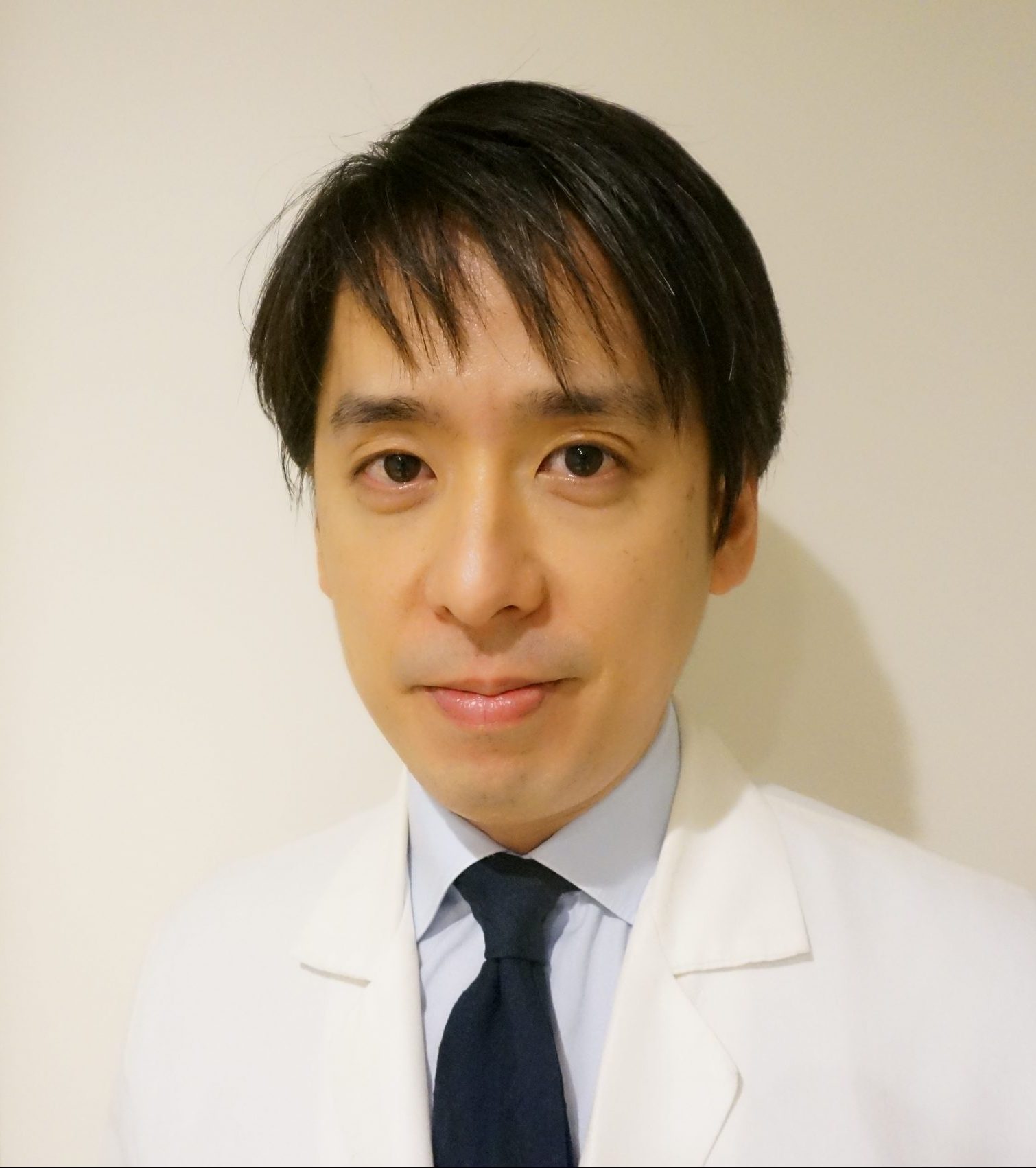整形外科の講師である加藤欽志氏が白衣を着て微笑んでいるポートレート。