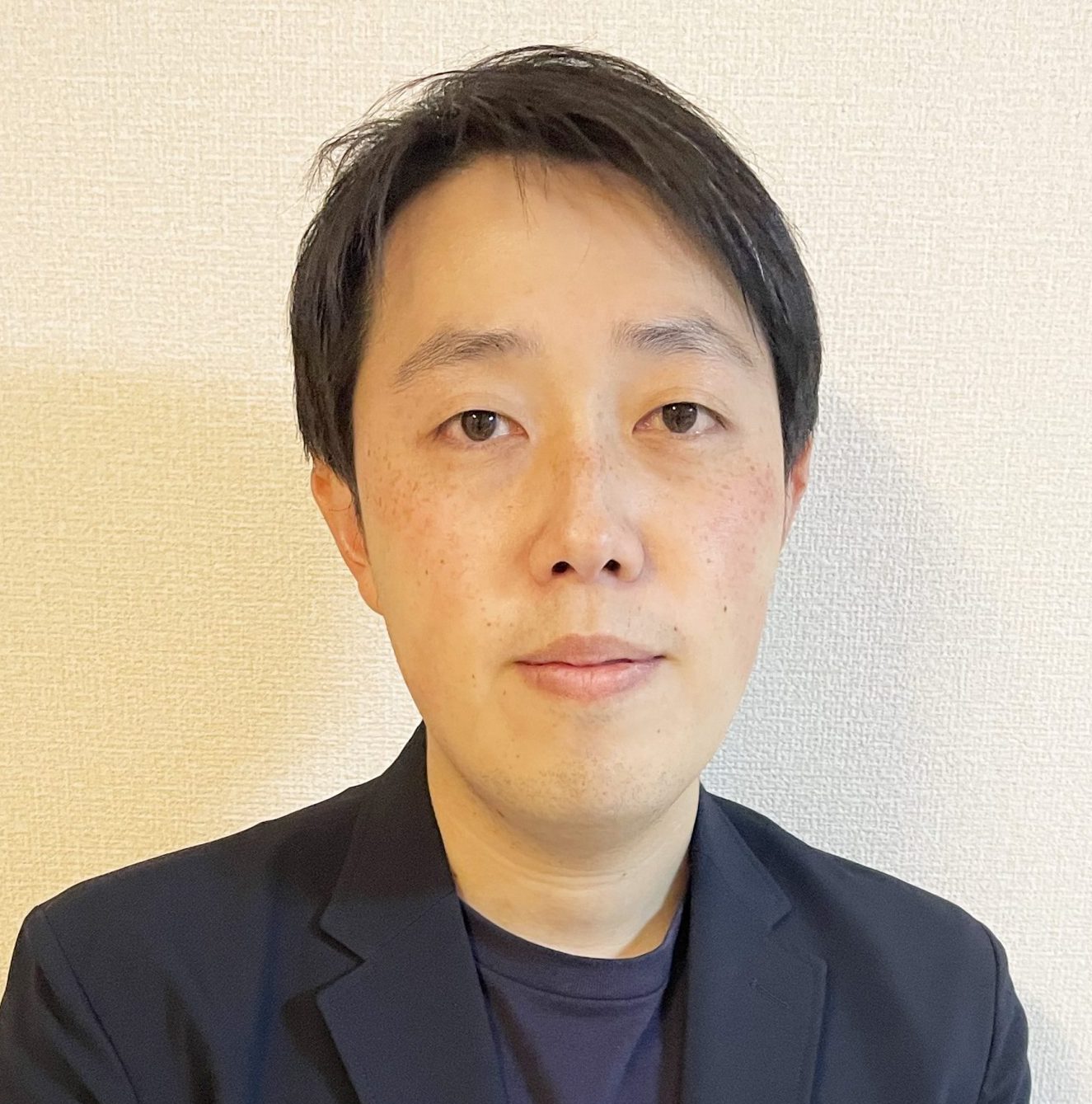中嶋正太郎准教授がスーツを着てカメラに向かって微笑んでいるポートレート。背景はシンプルな壁。