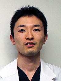 医療用白衣を着た男性のポートレート。彼は真剣な表情でカメラを見つめている。