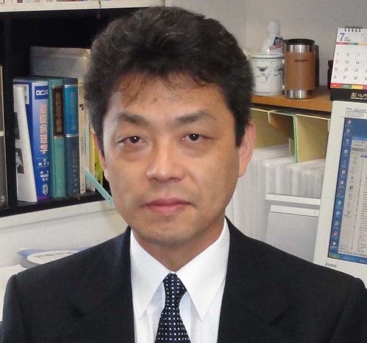 千葉英樹教授がスーツを着て微笑んでいるポートレート。背景には書籍や資料が並ぶ研究室の一部が見える。