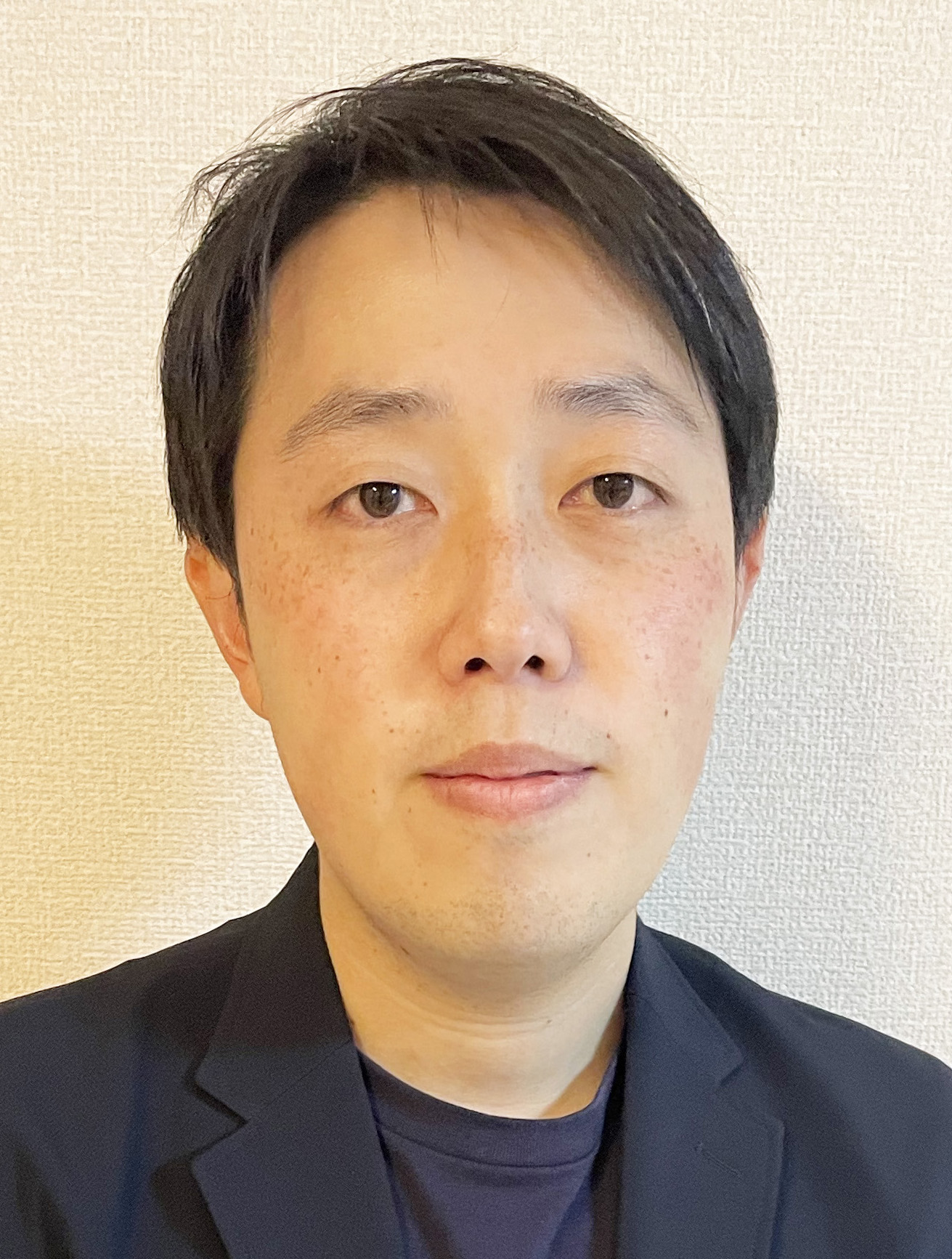 中嶋正太郎准教授のポートレート、黒いジャケットを着用し、真剣な表情でカメラを見つめている。