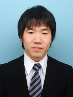 福島県立医科大学の助教、藤田雄也氏のスーツ姿のポートレート。背景は青色。