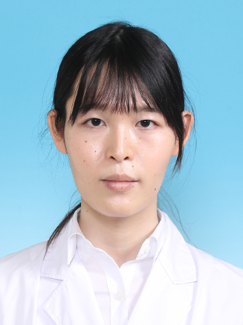 医療用白衣を着た女性が青い背景の前で真剣な表情をしているポートレート。