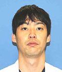 医療白衣を着た男性が青い背景の前で正面を向いている肖像写真。