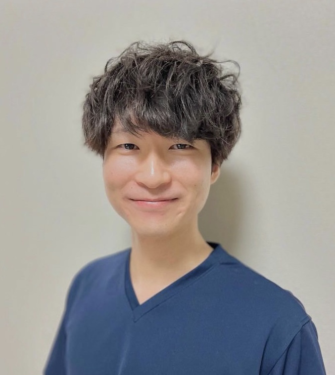 医療関係者の男性が微笑んでいるポートレート。青いスクラブを着用。