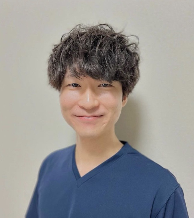 福島県立医科大学の助手、小河原崚氏のポートレート写真。白衣を着て微笑む姿。